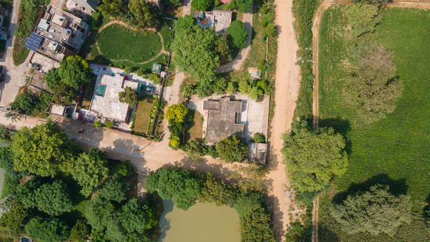 Lahore Pakistan 08 September 2026 Aerial view of a government office complex surrounded by lush green trees agricultural fields and dirt roads in Lahore Punjab Pakistan.