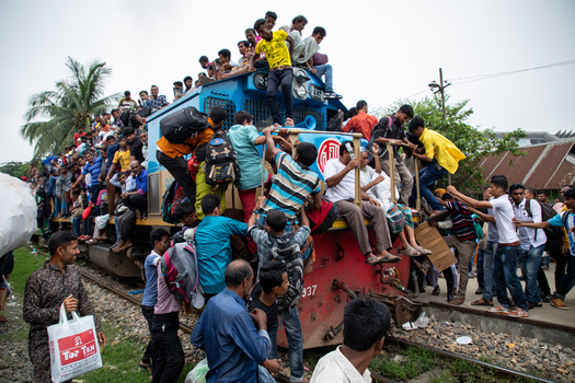 Dhaka Bangladesh 15 June 2018 View of a crowded train at Airport Railway Station with people sitting on the roof and hanging from the sides of the locomotive. Dhaka Bangladesh 15 June 2018 View of a crowded train at Airport Railway Station with people sitting on the roof and hanging from the sides of the locomotive.