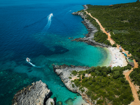 Aerial view of Aquarium Beach featuring turquoise waters rocky cliffs and lush green vegetation along the coastline in Jala Vlore County Albania. Aerial view of Aquarium Beach featuring turquoise waters rocky cliffs and lush green vegetation along the coastline in Jala Vlore County Albania.