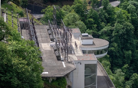 Aerial view of Verzasca Dam power station with electrical transformers and modern architecture surrounded by lush green forest Gordola Ticino Switzerland. Aerial view of Verzasca Dam power station with electrical transformers and modern architecture surrounded by lush green forest Gordola Ticino Switzerland.