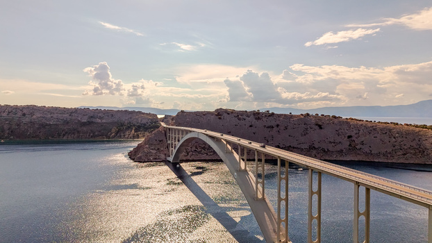 Aerial view of Krk Bridge spanning the Adriatic Sea connecting the mainland to the island of Krk with rocky cliffs and calm water in Smrika Primorje Gorski Kotar Croatia. Aerial view of Krk Bridge spanning the Adriatic Sea connecting the mainland to the island of Krk with rocky cliffs and calm water in Smrika Primorje Gorski Kotar Croatia.