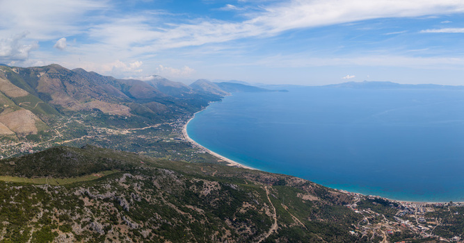 Aerial view of the rugged coastline and turquoise waters of the Ionian Sea with mountains and sandy beaches in Qeparo Fshat Vlore County Albania. Aerial view of the rugged coastline and turquoise waters of the Ionian Sea with mountains and sandy beaches in Qeparo Fshat Vlore County Albania.