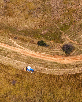 Aerial view of a tractor slashing dry vegetation along a dirt road to create a firebreak on a farm in Tzaneen Limpopo South Africa.