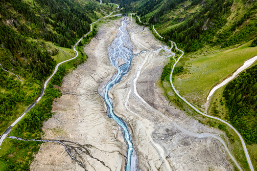Aerial view of the river flowing through the valley near Prutz surrounded by steep mountain slopes lush green forests and winding roads in Prutz Tyrol Austria. Aerial view of the river flowing through the valley near Prutz surrounded by steep mountain slopes lush green forests and winding roads in Prutz Tyrol Austria.