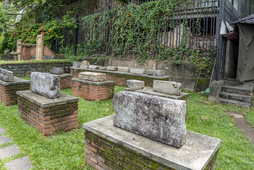 View of ancient stone artifacts displayed on brick pedestals within the historic grounds of the Sri Dalada Maligawa in Kandy Central Province Sri Lanka. View of ancient stone artifacts displayed on brick pedestals within the historic grounds of the Sri Dalada Maligawa in Kandy Central Province Sri Lanka.