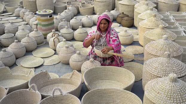 View of a woman weaving traditional baskets in Bogura Bangladesh. View of a woman weaving traditional baskets in Bogura Bangladesh.