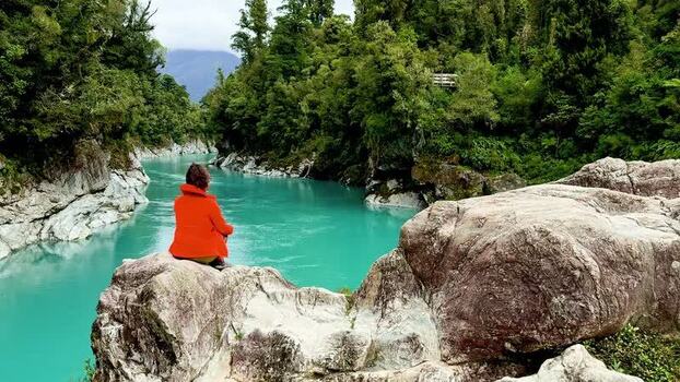 View of a person by a turquoise river in a gorge New Zealand. View of a person by a turquoise river in a gorge New Zealand.