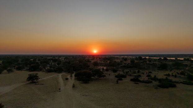 Aerial view of the Okavango Delta at sunset with a vehicle on a dirt track sparse trees and a river in the distance Okavango Delta North West District Botswana. Aerial view of the Okavango Delta at sunset with a vehicle on a dirt track sparse trees and a river in the distance Okavango Delta North West District Botswana.