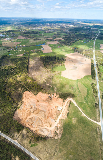 Aerial view of a sand and gravel quarry surrounded by green fields forests and a road in Latvia. Aerial view of a sand and gravel quarry surrounded by green fields forests and a road in Latvia.