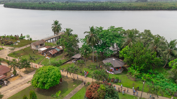Aerial view of a riverside park with lush palm trees a small pier and people walking along paths in Minima Rivers Nigeria.