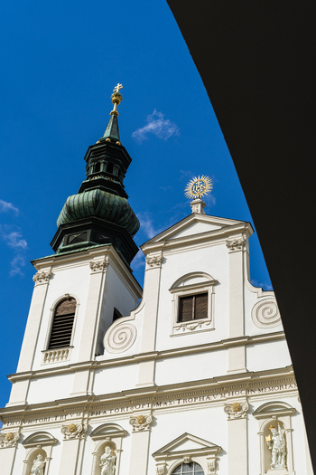 View of the Baroque facade and green copper spire of the Gardekirche under a clear blue sky in Vienna Vienna Austria. View of the Baroque facade and green copper spire of the Gardekirche under a clear blue sky in Vienna Vienna Austria.