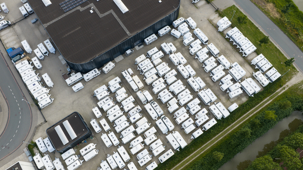 Purmerend Netherlands 15 June 2026 Aerial view of a large parking lot filled with numerous white caravans parked in organized rows next to a modern industrial building. Purmerend Netherlands 15 June 2026 Aerial view of a large parking lot filled with numerous white caravans parked in organized rows next to a modern industrial building.