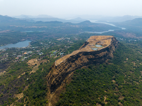 Aerial view of Korigad Fort a historic hill fort with stone ramparts and water reservoirs set against lush green hills and a nearby lake in Peth Shahapur Maharashtra India. Aerial view of Korigad Fort a historic hill fort with stone ramparts and water reservoirs set against lush green hills and a nearby lake in Peth Shahapur Maharashtra India.