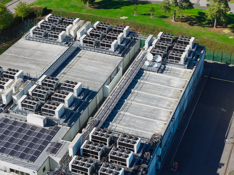 Aerial view of a modern data center roof featuring rows of industrial cooling units solar panels and satellite dishes United Kingdom.