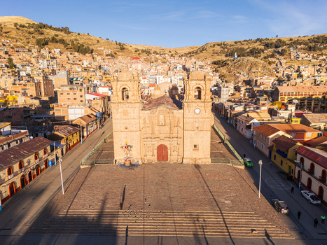 Aerial view of the historic Puno Cathedral situated in the Plaza de Armas surrounded by colonial architecture and urban hills under a clear sky in Puno Puno Peru.