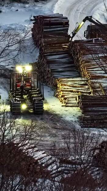 Aerial view of forestry machine moving logs in snowy forest LATVIA.