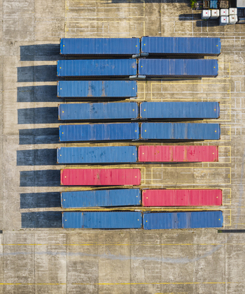 Aerial view of rows of blue and red shipping containers neatly arranged in a logistics yard with long shadows cast on the concrete ground in Taiwan. Aerial view of rows of blue and red shipping containers neatly arranged in a logistics yard with long shadows cast on the concrete ground in Taiwan.