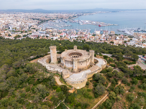 Aerial view of Castillo de Bellver surrounded by pine forest overlooking the city and harbor in Palma Illes Balears Spain.