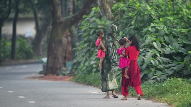 View of women carrying children along a roadside in Bogura Bangladesh.