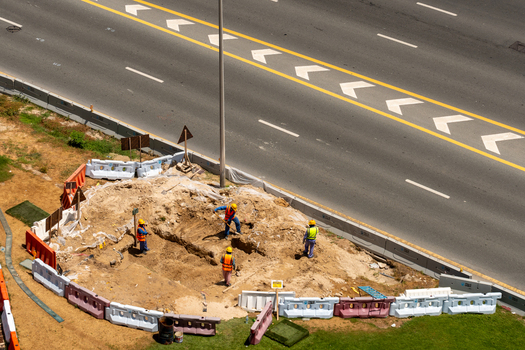 Aerial view of construction workers in safety vests digging a trench at a construction site in Dubai Dubai United Arab Emirates. Aerial view of construction workers in safety vests digging a trench at a construction site in Dubai Dubai United Arab Emirates.