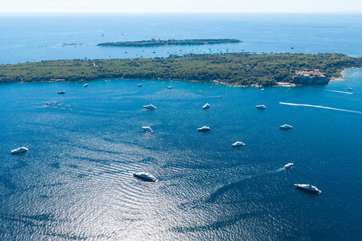Aerial view of luxury yachts anchored in the blue waters near the Lerins Islands off the coast of Antibes Provence Alpes Cote d Azur France. Aerial view of luxury yachts anchored in the blue waters near the Lerins Islands off the coast of Antibes Provence Alpes Cote d Azur France.