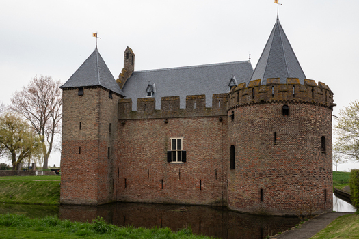 View of Radboud Castle featuring medieval brick walls towers battlements and a moat under an overcast sky in Medemblik Noord Holland Netherlands. View of Radboud Castle featuring medieval brick walls towers battlements and a moat under an overcast sky in Medemblik Noord Holland Netherlands.