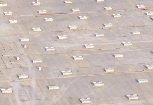 Aerial view of the flat roof of a large industrial building featuring numerous rectangular skylights arranged in a grid pattern in Kowale Pomeranian Voivodeship Poland. Aerial view of the flat roof of a large industrial building featuring numerous rectangular skylights arranged in a grid pattern in Kowale Pomeranian Voivodeship Poland.