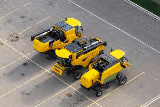 Aerial view of three yellow combine harvesters parked in a paved lot at a harvesting machinery producer facility in Plock Masovian Voivodeship Poland. Aerial view of three yellow combine harvesters parked in a paved lot at a harvesting machinery producer facility in Plock Masovian Voivodeship Poland.