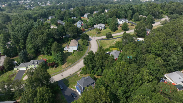 Aerial view of a suburban neighborhood with detached houses winding roads and lush green trees in Shrewsbury Massachusetts United States.