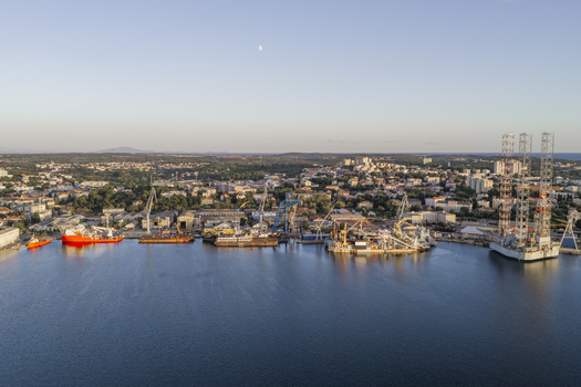 Aerial view of Pola Port featuring industrial ships cranes and the surrounding cityscape under a clear sky in Pula Istarska zupanija Croatia. Aerial view of Pola Port featuring industrial ships cranes and the surrounding cityscape under a clear sky in Pula Istarska zupanija Croatia.