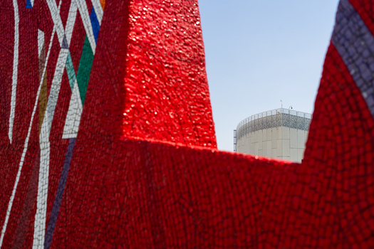 Bratislava Slovakia 09 May 2026 View of a vibrant red mosaic sculpture with geometric patterns and a modern building in the background under a clear blue sky.