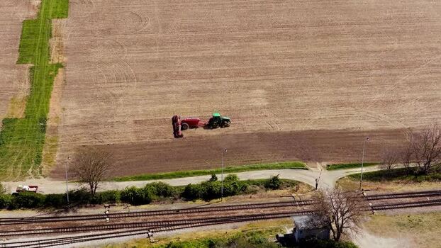 Aerial view of a tractor working in a field by a railway Czechia. Aerial view of a tractor working in a field by a railway Czechia.