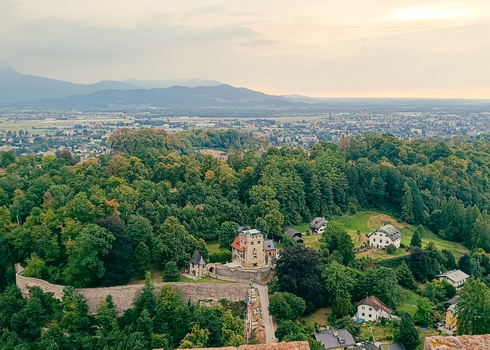 View of the historic Hohensalzburg Fortress surroundings with lush green trees stone walls and traditional houses nestled in the landscape of Salzburg Salzburg Austria. View of the historic Hohensalzburg Fortress surroundings with lush green trees stone walls and traditional houses nestled in the landscape of Salzburg Salzburg Austria.