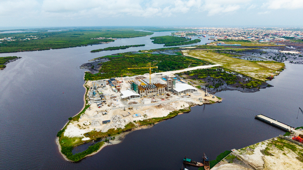 Aerial view of a construction site with a yellow crane and concrete structures on an island surrounded by a lagoon and lush vegetation in Lagos Lagos Nigeria.
