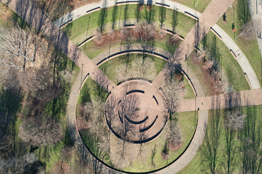 Aerial view of circular park design with concentric walking paths and bare trees casting long shadows on green lawns Turin Piedmont Italy. Aerial view of circular park design with concentric walking paths and bare trees casting long shadows on green lawns Turin Piedmont Italy.