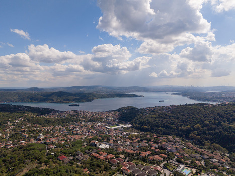 Aerial view of the Bosphorus strait in Istanbul featuring lush green hills residential neighborhoods with red tiled roofs and ships navigating the blue waters in Istanbul Istanbul Turkiye.