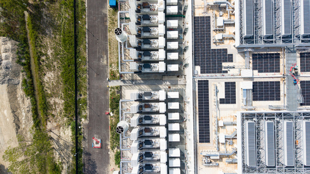Aerial view of a modern data center campus with rows of cooling units solar panels and industrial infrastructure in Melegnano Lombardy Italy.