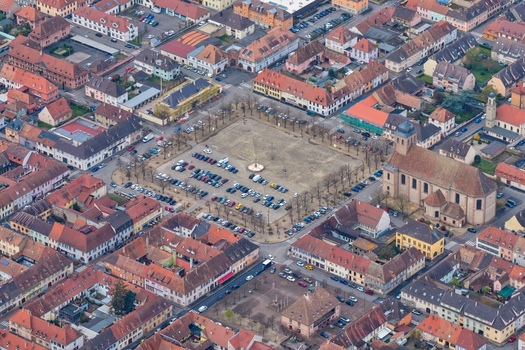 Aerial view of the meticulously planned grid layout and central square with buildings adorned with red tile roofs creating a warm contrast against the pale sky Neuf Brisach Grand Est France.