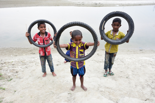 Kushtia Khulna Division Bangladesh 12 March 2020 View of three young boys playing with bicycle tires on a sandy riverbank. Kushtia Khulna Division Bangladesh 12 March 2020 View of three young boys playing with bicycle tires on a sandy riverbank.