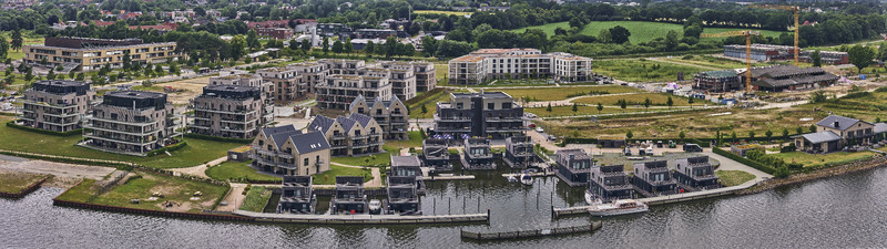 Schleswig Germany 01 July 2026 Aerial view of the Quatier Schlei Leben redevelopment featuring modern floating houses in the harbor on the former Bundeswehr base surrounded by green landscapes.