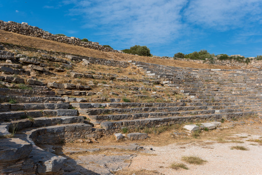 View of the Ancient Theatre of Thorikos featuring stone seating tiers and archaeological ruins under a blue sky in Thoricus Greece.