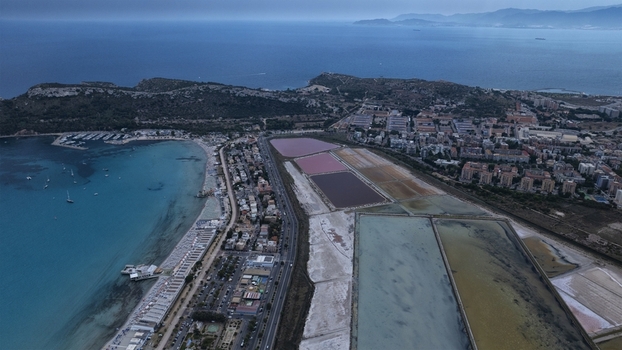 Aerial view of the pink salt pans of Molentargius and Poetto beach with the marina and urban skyline under a twilight sky in Cagliari Sardinia Italy. Aerial view of the pink salt pans of Molentargius and Poetto beach with the marina and urban skyline under a twilight sky in Cagliari Sardinia Italy.