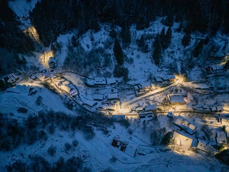 Aerial view of the village of Spania Dolina at night with snow covered rooftops and glowing streetlights in a dark forest valley Spania Dolina Banska Bystrica Region Slovakia. Aerial view of the village of Spania Dolina at night with snow covered rooftops and glowing streetlights in a dark forest valley Spania Dolina Banska Bystrica Region Slovakia.