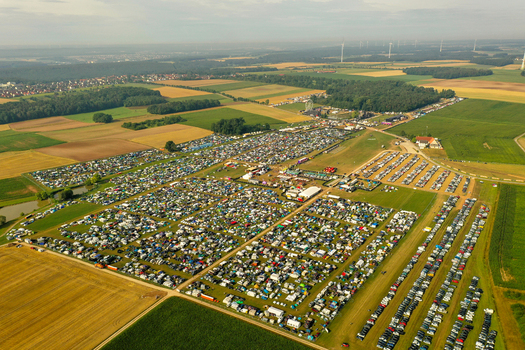 Aerial view of the Open Beatz Festival campsite featuring rows of tents and parked cars surrounded by agricultural fields and forests in Herzogenaurach Bayern Germany.
