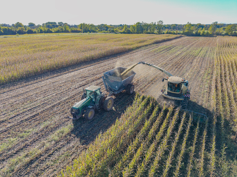 Green Bay Wisconsin United States 25 September 2026 Aerial view of a combine harvester chopping corn for silage into a tractor pulled trailer in a large agricultural field.