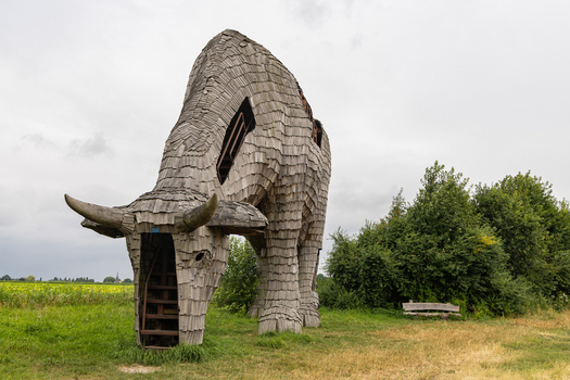 View of the large wooden bull sculpture known as De Melkfabriek standing in a grassy field under a cloudy sky in Esbeek Noord Brabant Netherlands.