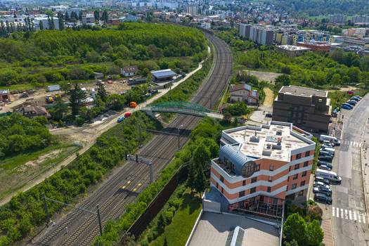 Aerial view of railway tracks passing through a green urban area with a pedestrian bridge and modern buildings in Prague Prague Czechia.