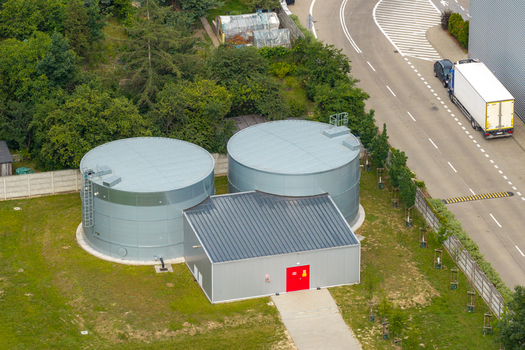 Aerial view of two large grey industrial water tanks connected to a small utility building with a bright red door in an industrial area in Warsaw Masovian Voivodeship Poland. Aerial view of two large grey industrial water tanks connected to a small utility building with a bright red door in an industrial area in Warsaw Masovian Voivodeship Poland.
