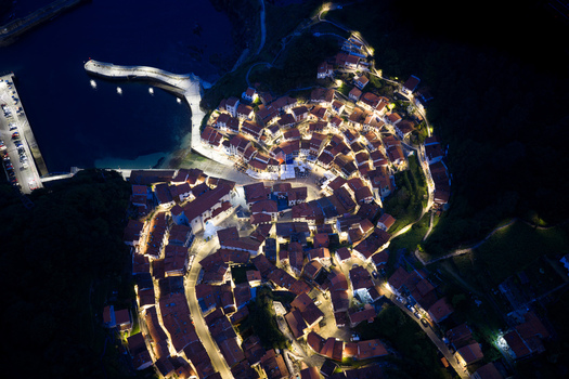 Aerial view of Cudillero at night with glowing houses arranged in an amphitheater shape around the dark harbor Cudillero Asturias Spain. Aerial view of Cudillero at night with glowing houses arranged in an amphitheater shape around the dark harbor Cudillero Asturias Spain.