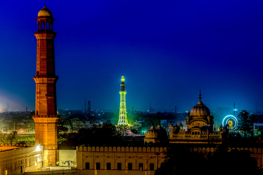 View of the illuminated Badshahi Mosque and Minar e Pakistan at night featuring historic Mughal architecture glowing minarets and a vibrant city skyline in Lahore Punjab Pakistan. View of the illuminated Badshahi Mosque and Minar e Pakistan at night featuring historic Mughal architecture glowing minarets and a vibrant city skyline in Lahore Punjab Pakistan.